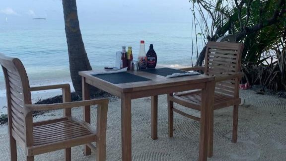 Romantic beachfront dinner setting on a calm Maldivian shore with an ocean view.