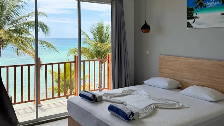 Palm trees beside turquoise water at a relaxed Maldivian beachfront setting.